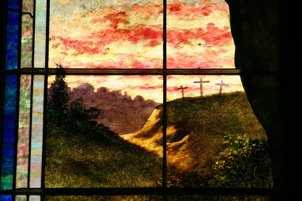 Look at the details of three distant crosses in this snippet of a stained glass window.