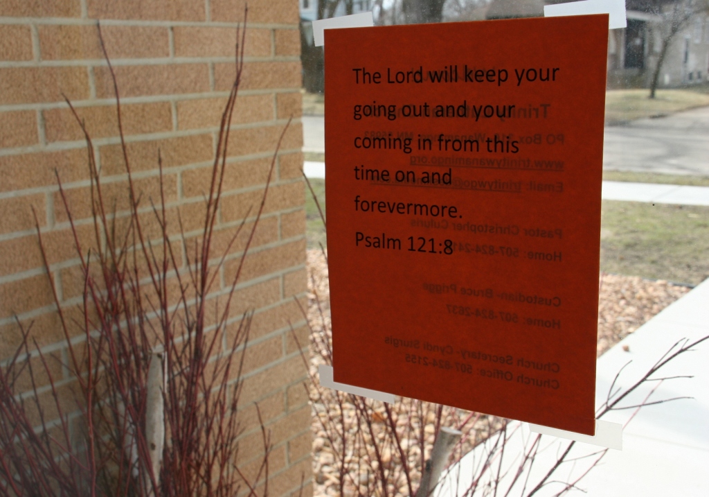 A final message for worshipers is posted on a window next to an exterior front door.
