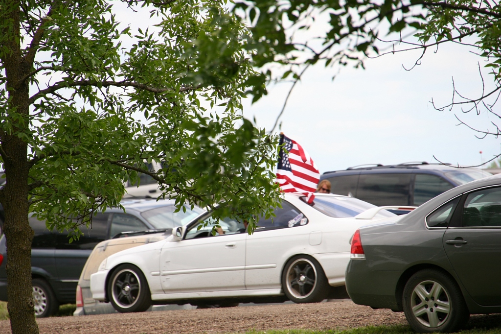 A flag bedecked car passes the festival grounds.